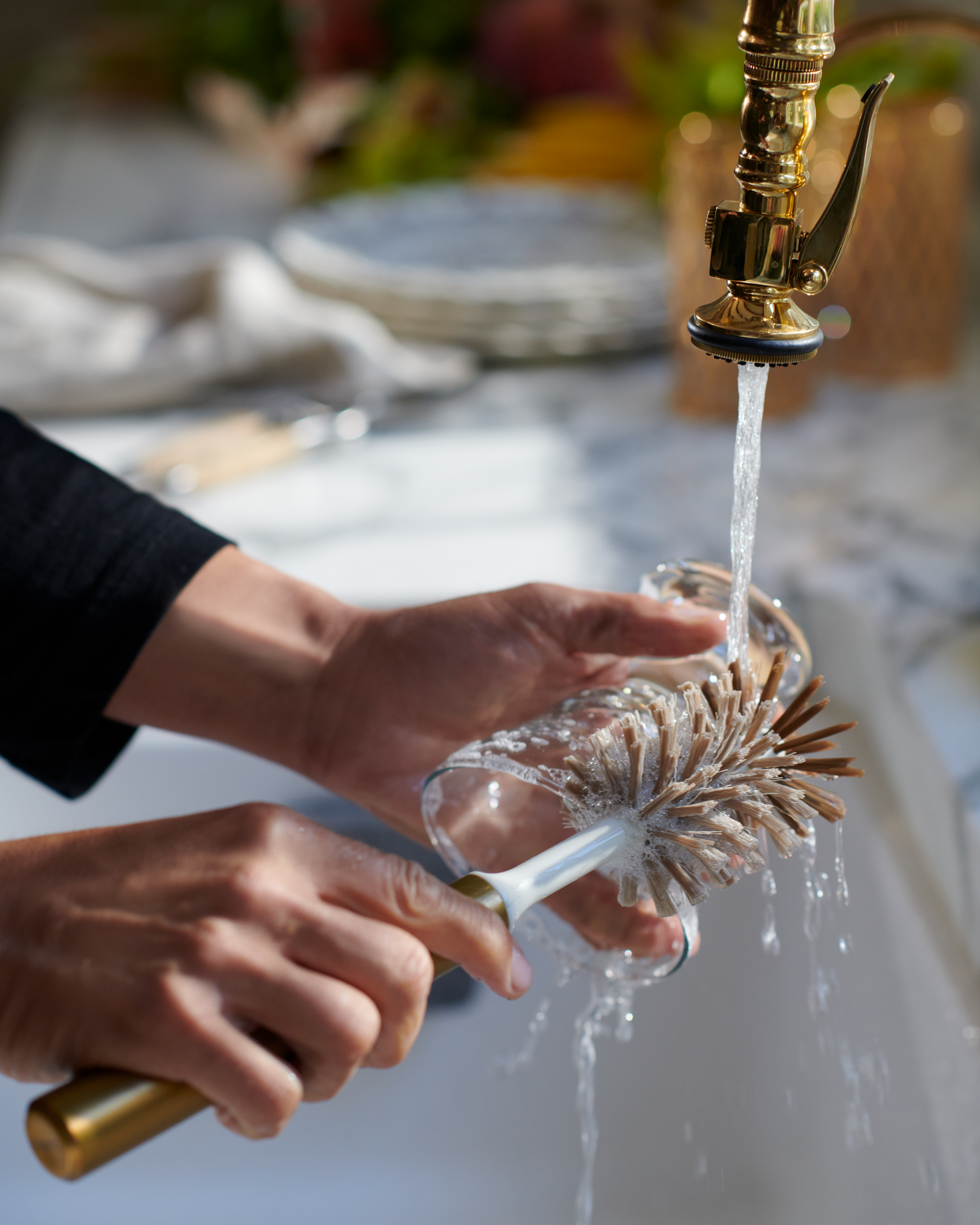 Person cleaning bottle with Curio Homegoods Brass Ionic Bottle Brush in kitchen sink
