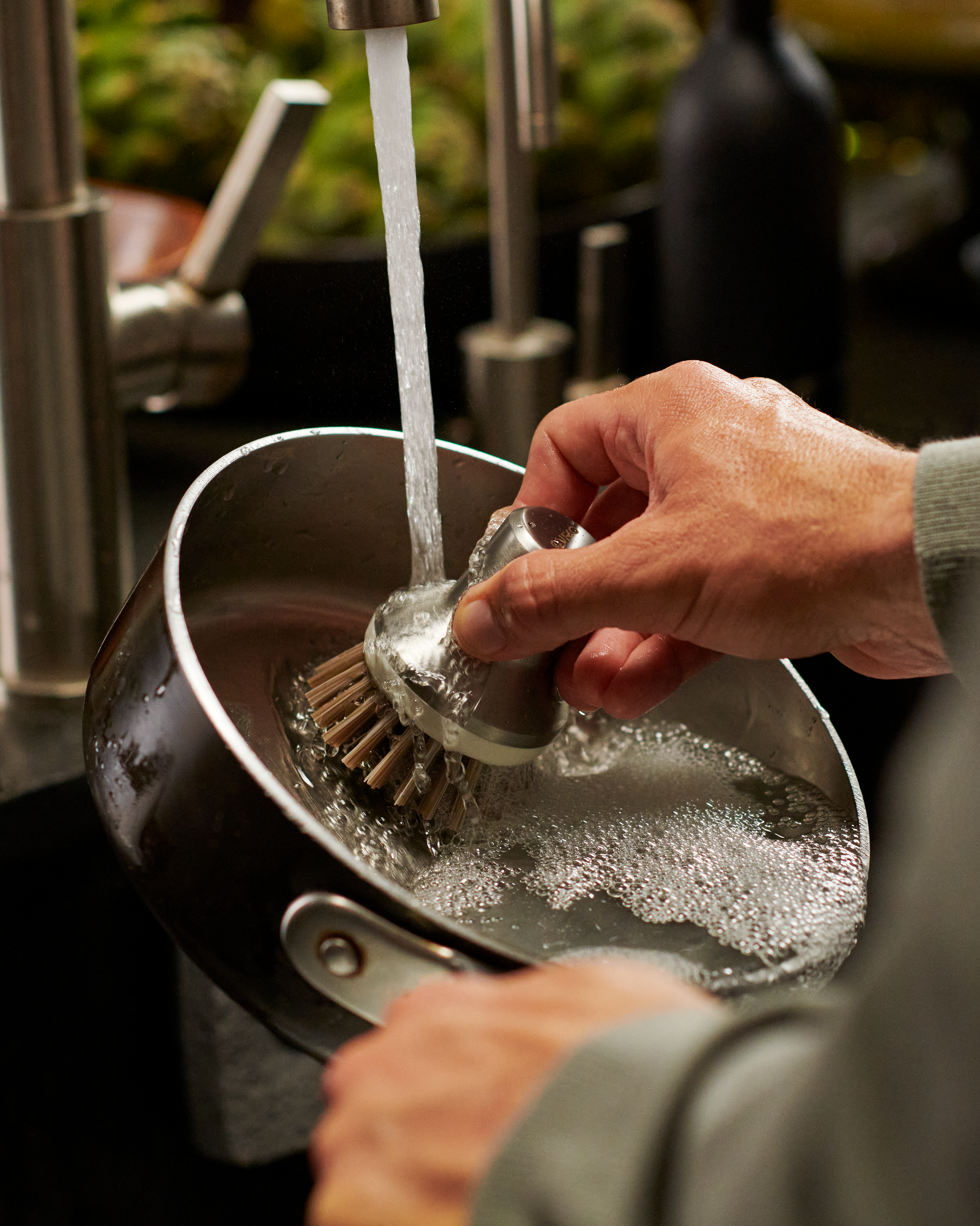 Person scrubbing pot with Curio Homegoods Stainless Steel Ionic Palm Brush