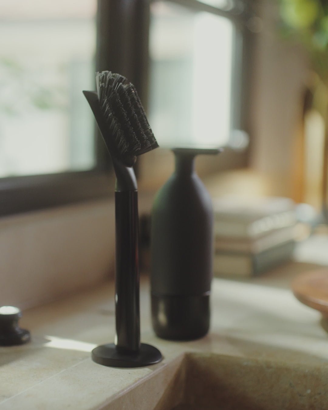 Video of a person grabbing Curio Homegoods Ionic Dish Brush in Onyx to clean dishes