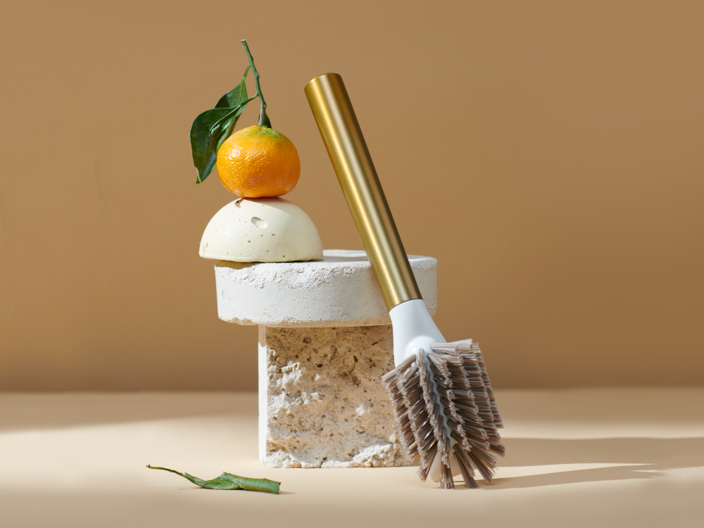 Curio Homegoods Brass Ionic Dish Brush with brown background and fruits