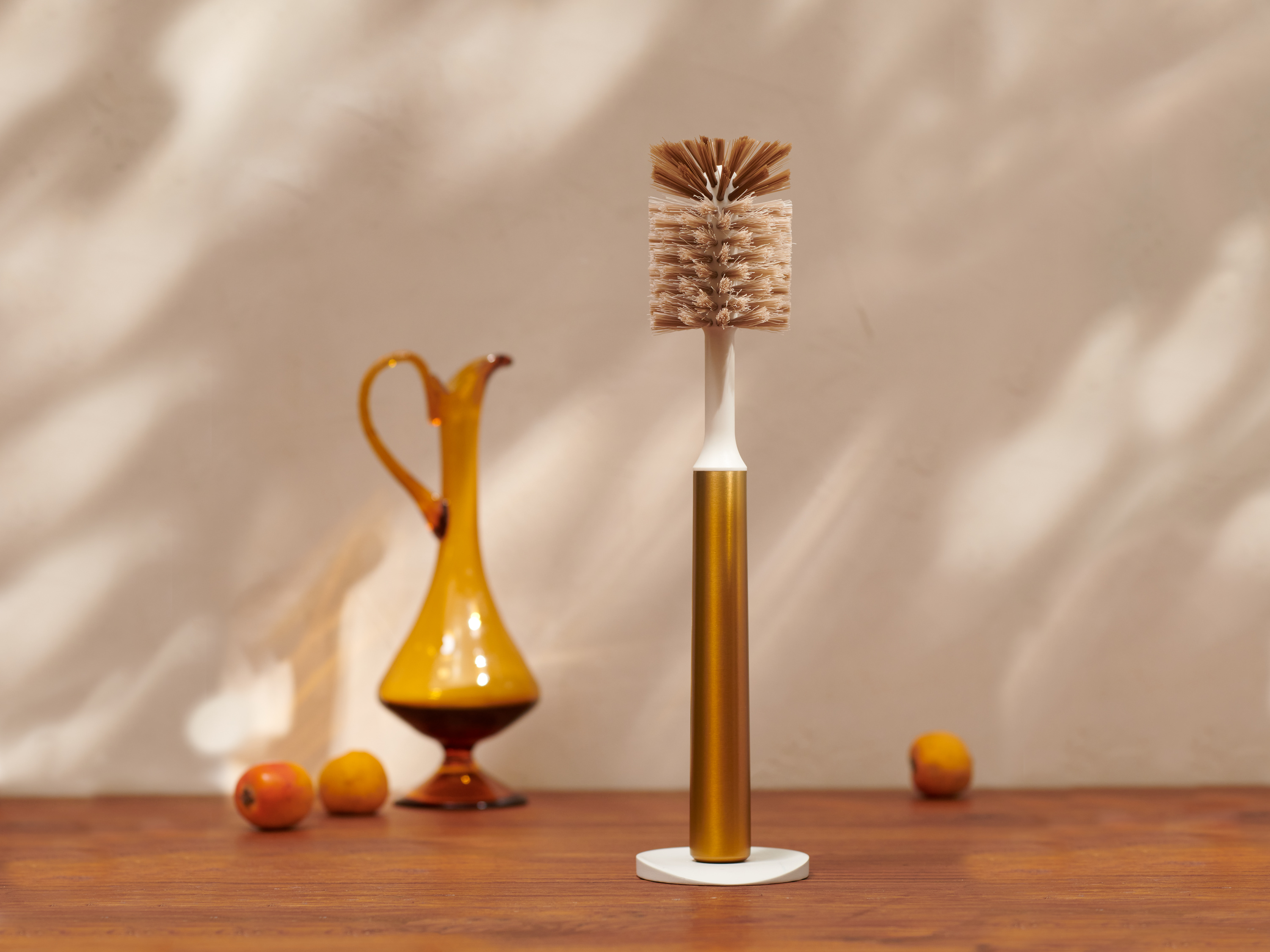 Curio Homegoods Brass Ionic Bottle Brush with vase and fruits in the background