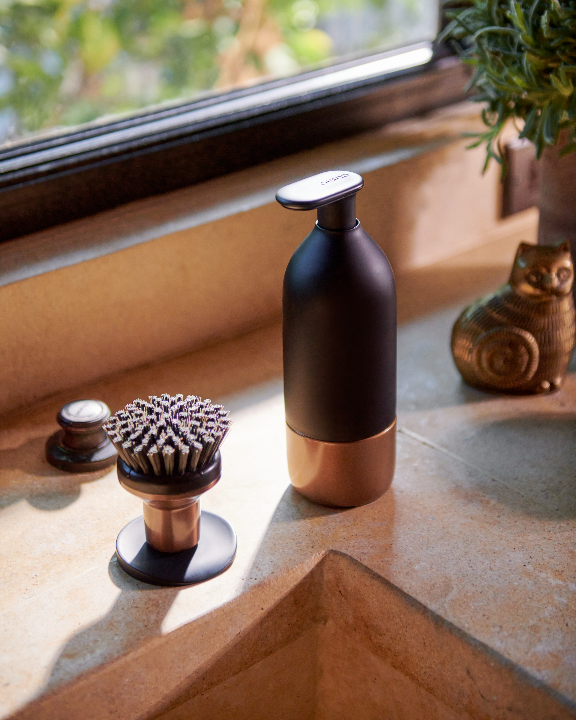 Closeup of Curio Homegoods Ionic Palm Brush in Bronze standing on kitchen counter