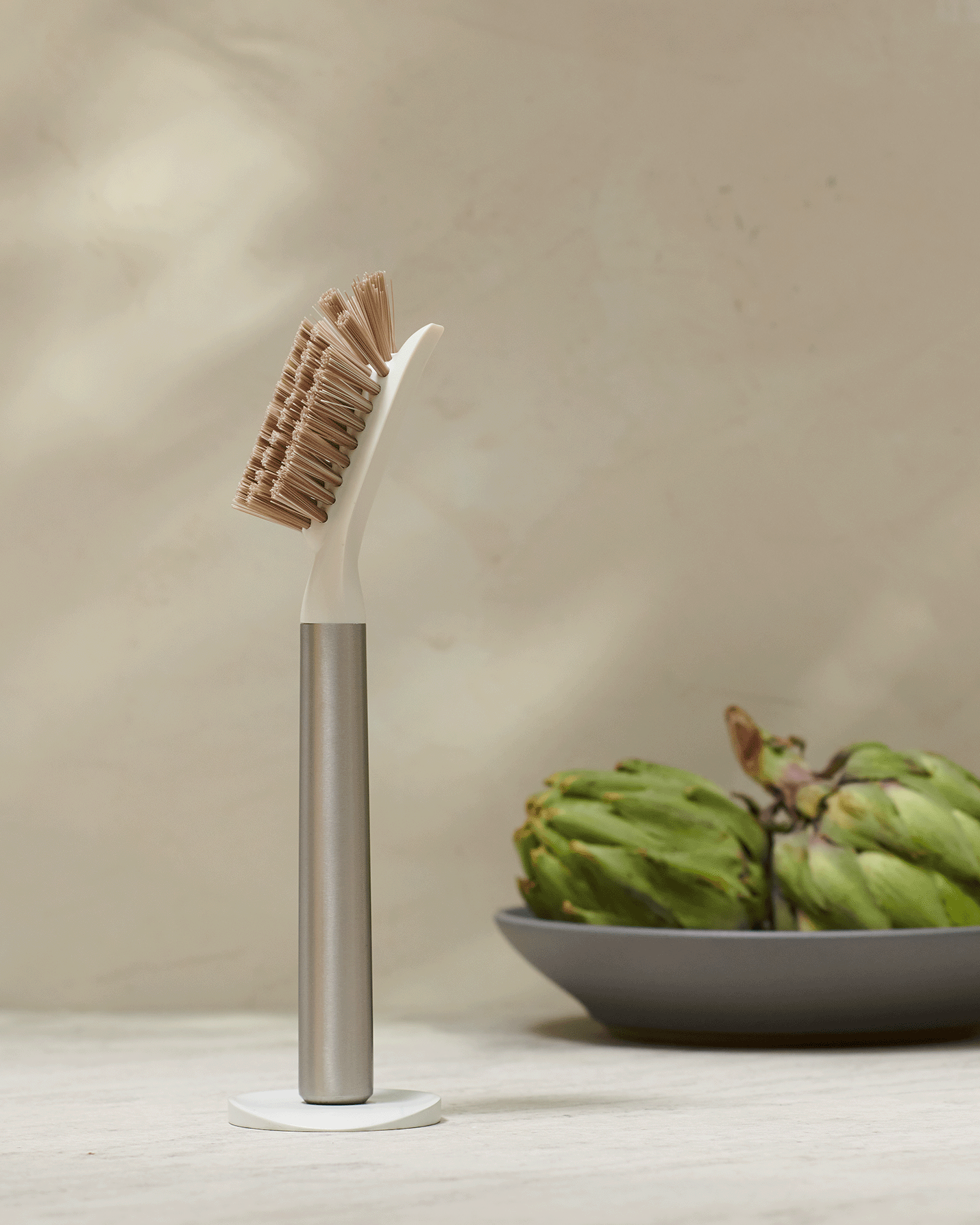 Curio Homegoods Ionic Dish Brush in Stainless Steel standing with brown background