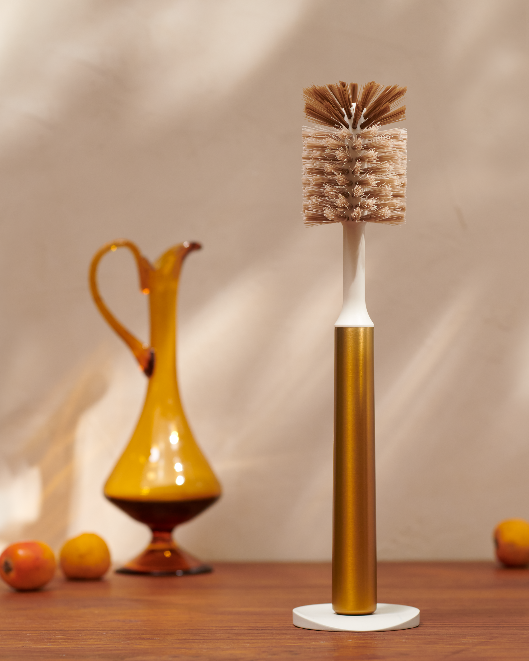 Curio Homegoods Brass Ionic Bottle Brush with vase and fruits in the background